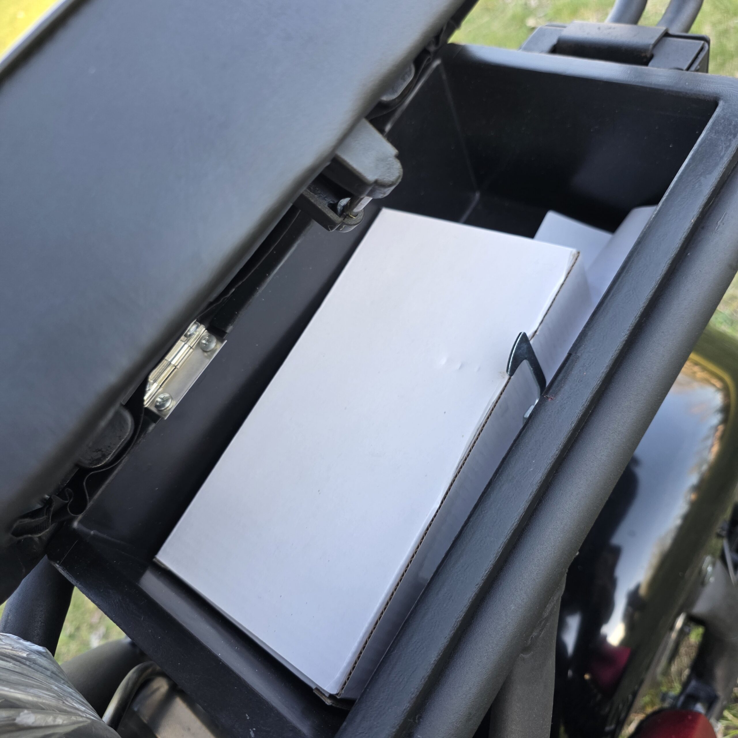 Atidarytas CityCoco motorolerio grindų skyrius su matoma balta ličio jonų baterija